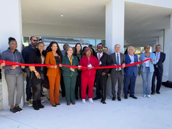 Folks standing in front of Meridian Point holding red ribbon for Ribbon Cutting Ceremony