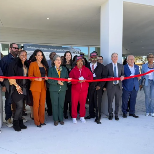 Folks standing in front of Meridian Point holding red ribbon for Ribbon Cutting Ceremony